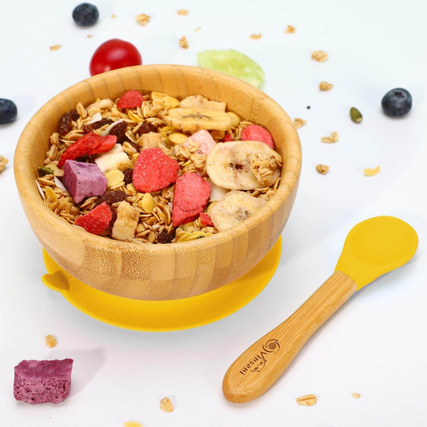 Vinsani bamboo bowl and spoon set filled with colorful granola, featuring a yellow silicone base for kids' mealtimes.