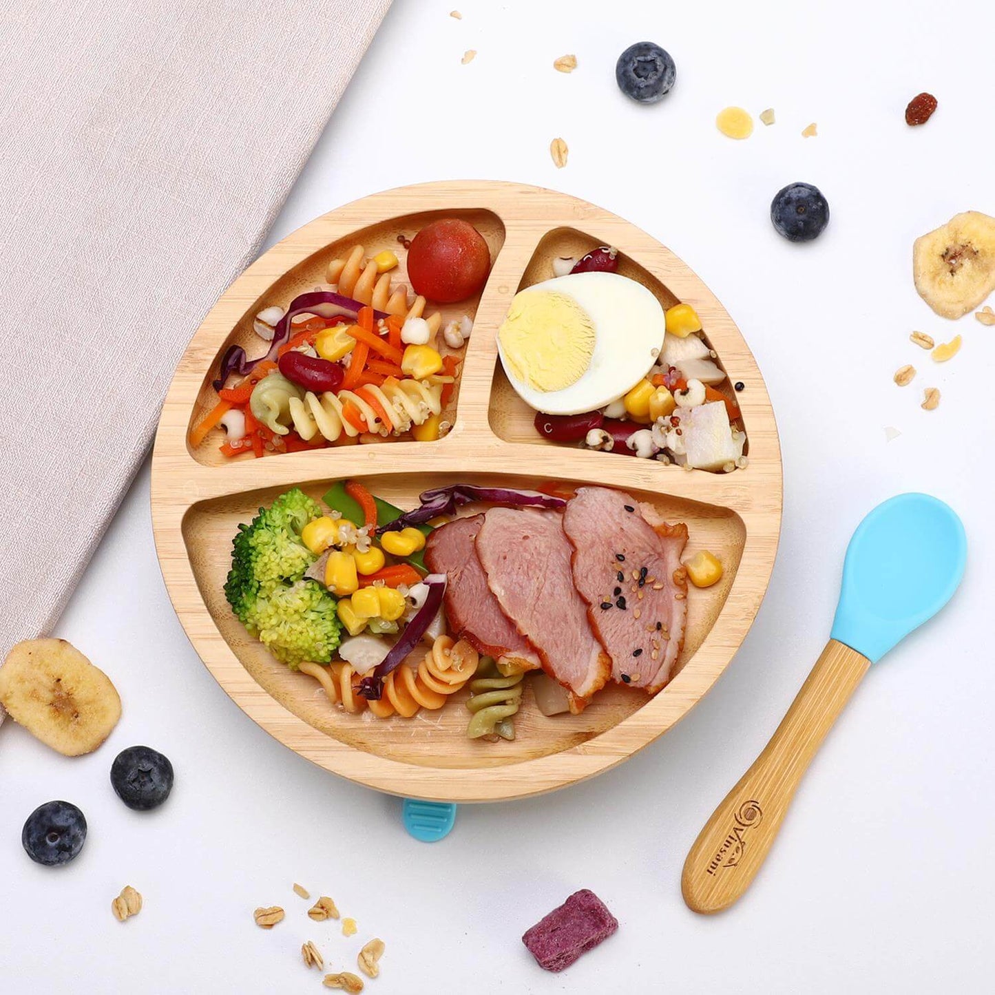 Natural bamboo kids plate with sections, healthy food, and a blue silicone spoon, ideal for toddlers and easy to clean.