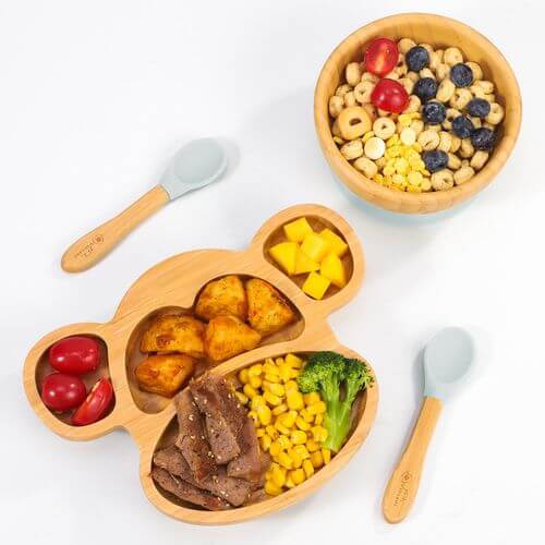 Vinsani Bamboo Monkey Plate with sections filled with healthy food, accompanied by a bowl of cereal and two spoons for kids.