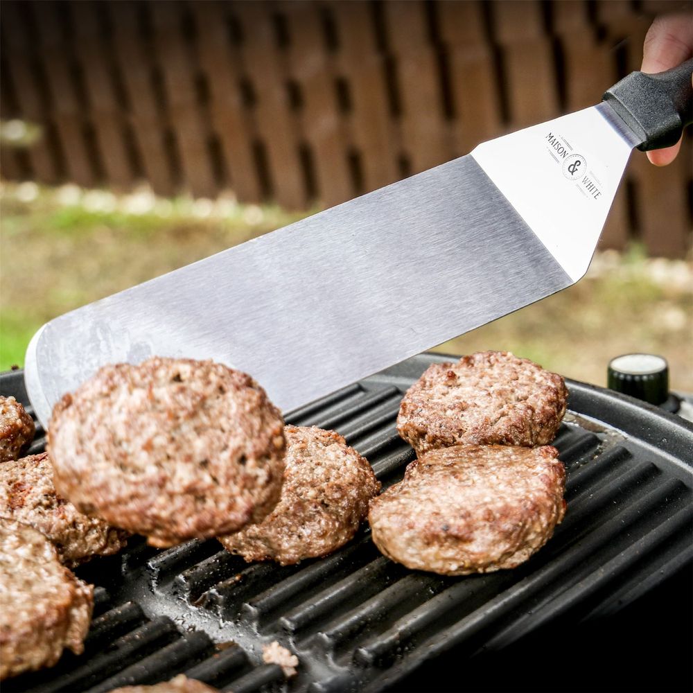 Stainless Steel Spatula In Use Flipping Burger On BBQ