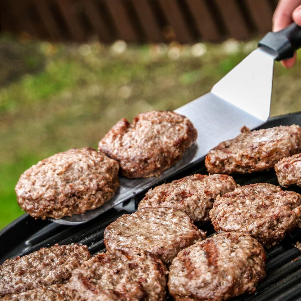 Stainless Steel Spatula In Use Flipping Burgers On BBQ